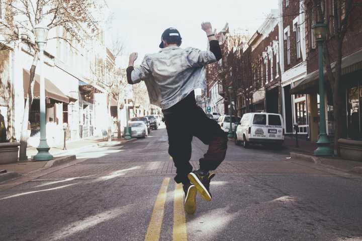 Mand er glad og hopper på en gade