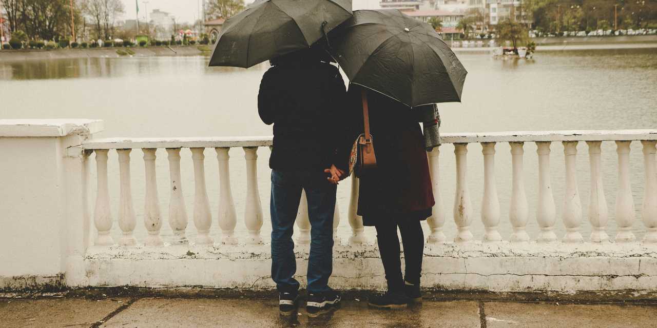 A couple standing by a pond hand-in-hand