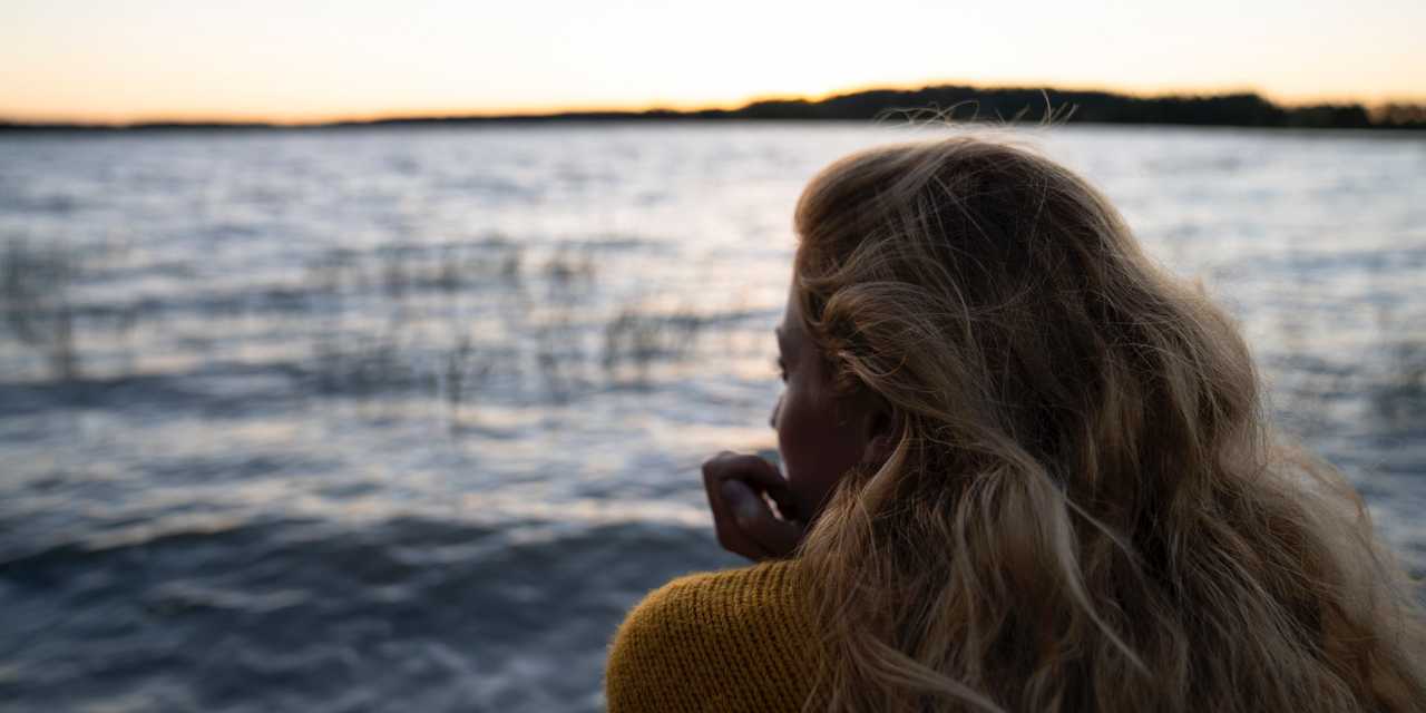 Nainen katsoo järvelle
