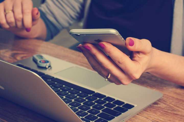 Person som sitter vid mobiltelefon och dator