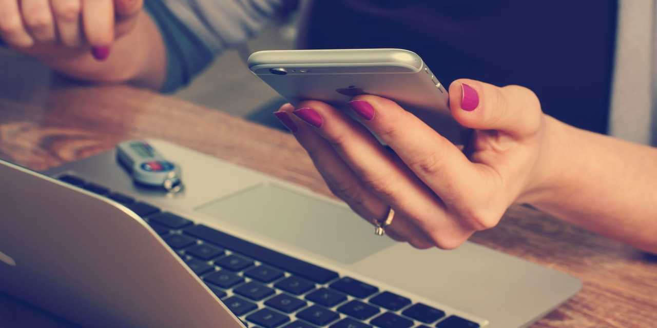 Person som sitter vid mobiltelefon och dator