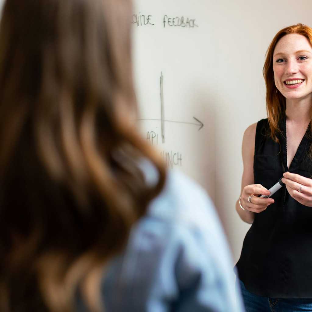 två personer som pratar vid en white board