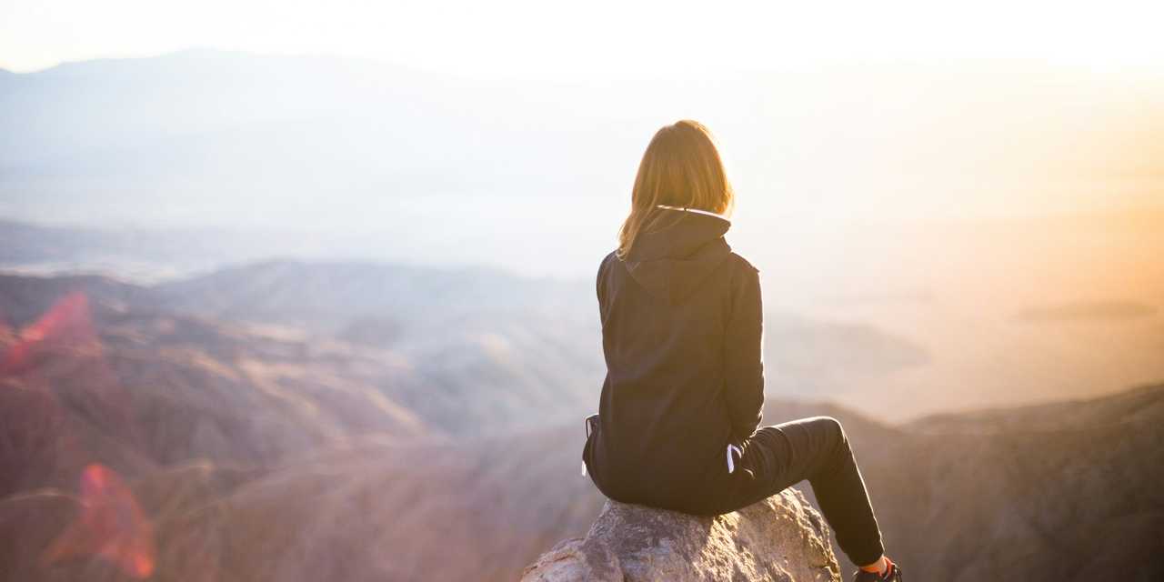 A woman sitting on the peak of a mountain