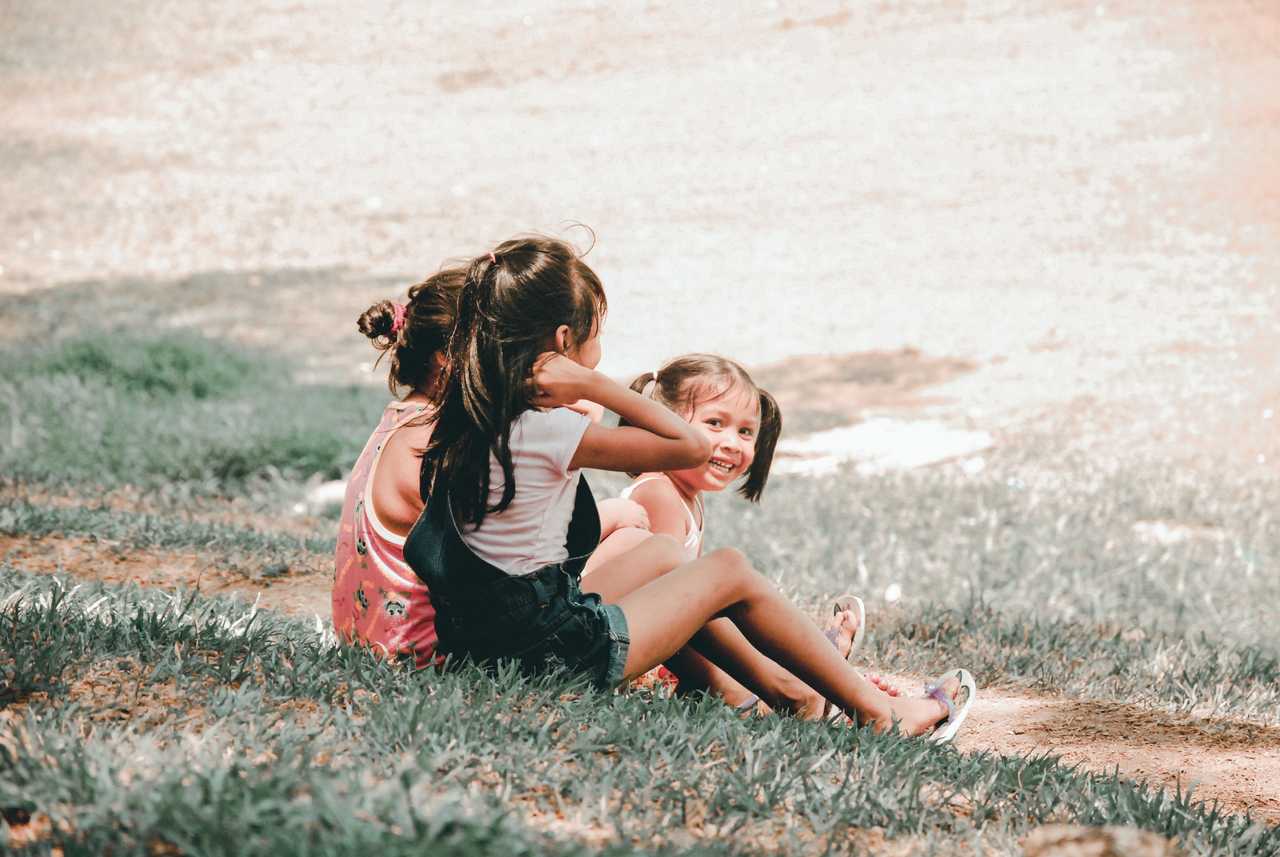 re barn som sitter på en gräsmatta