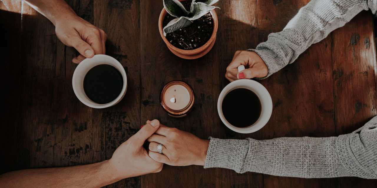et par sidder og drikker kaffe på en cafe og holder i hånd