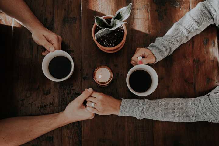 et par sidder og drikker kaffe på en cafe og holder i hånd
