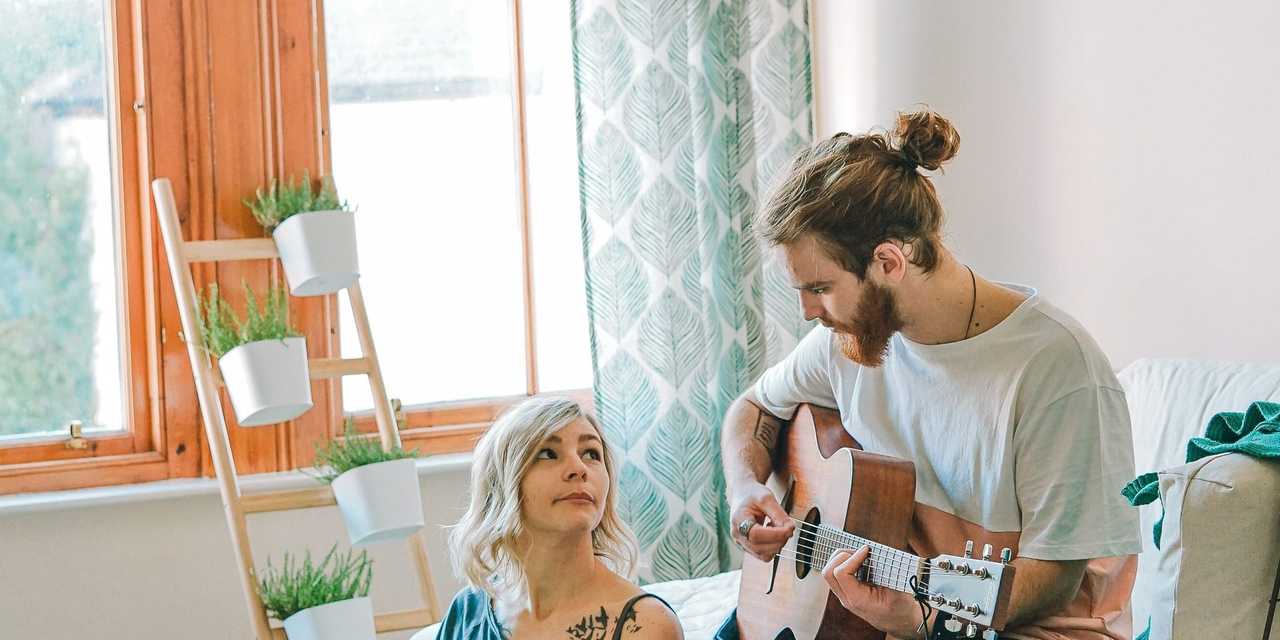To personer i rummet. Den anden spiller guitar.