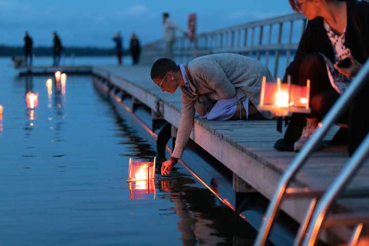 People placing a candle on water from a dock