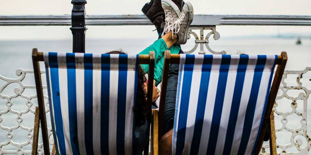 People lying on sun chairs by the sea