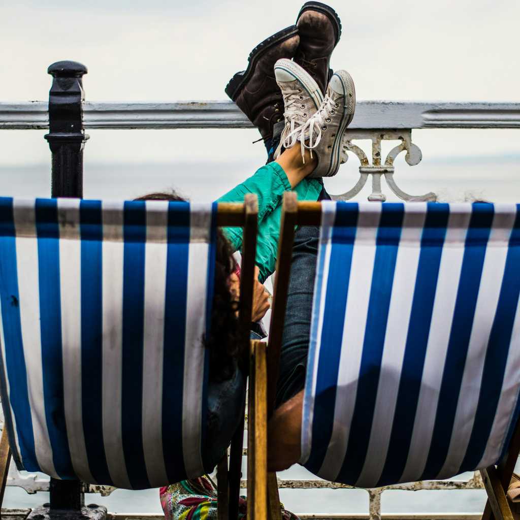 People lying on sun chairs by the sea