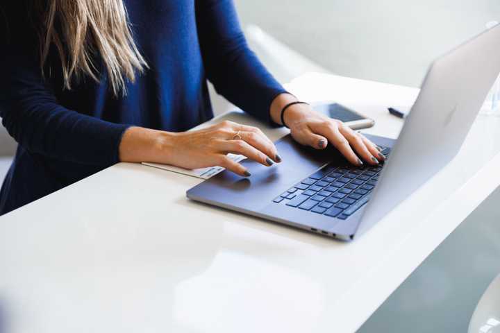 Nainen kirjoittaa kannettavalla tietokoneella