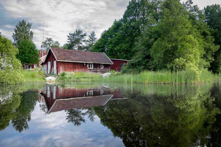 Gammalt rött hus vid en liten sjö