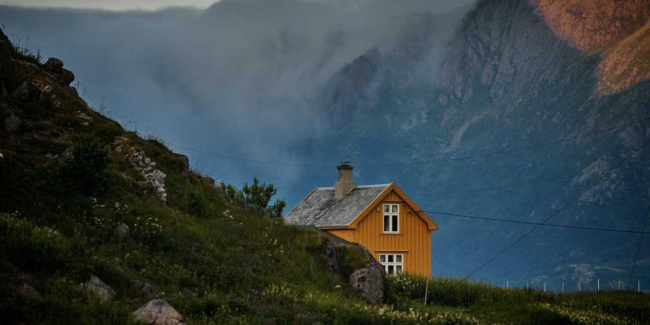 Keltainen talo maaseudulla. Vuoria taustalla. 