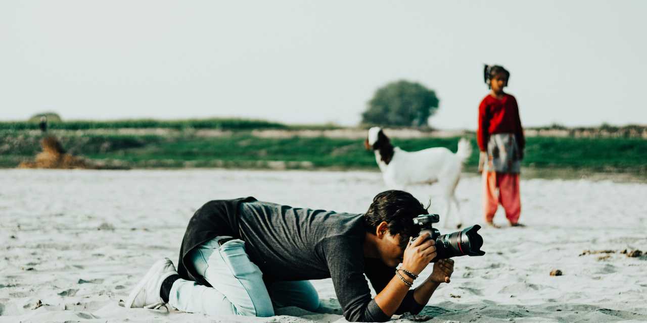 A person lying on sand and taking a picture