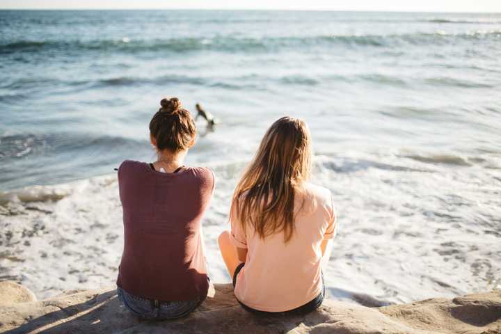 Kaksi ystävää istuu meren rannalla