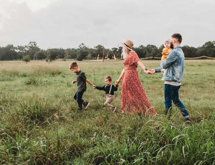 en familie på fem holder i hånd og går i naturen