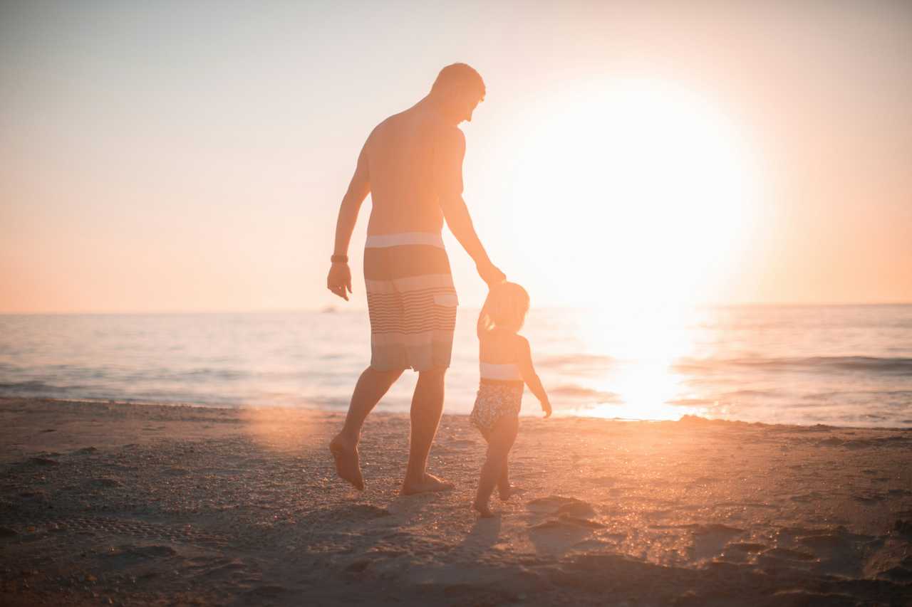 pappa och barn går på stranden