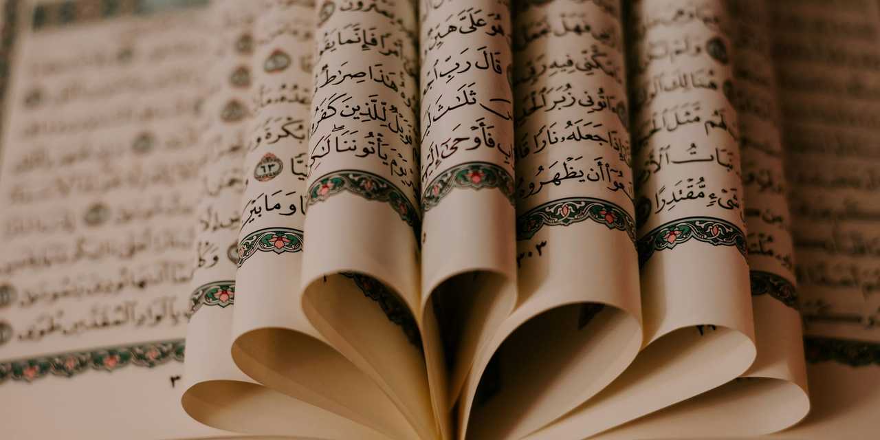 Sidor i en Koran vikta i mittuppslaget som en blomma. 