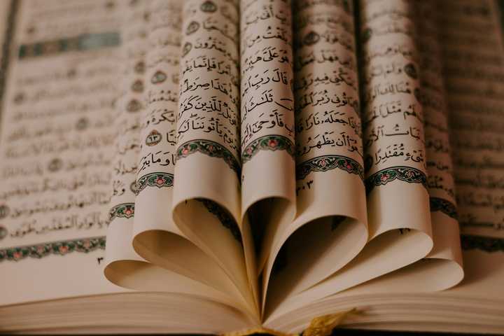 Sidor i en Koran vikta i mittuppslaget som en blomma. 
