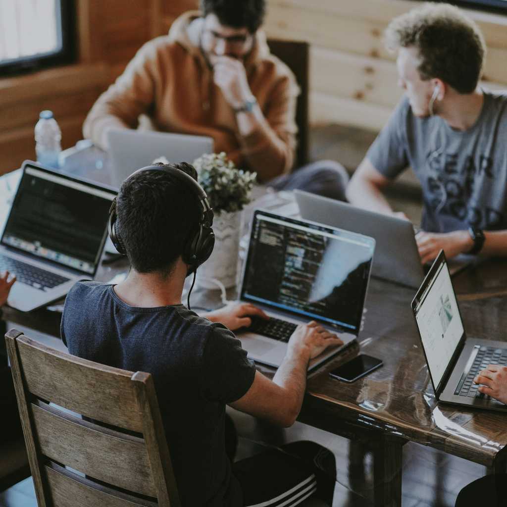 A group of developers gathered around table to code.