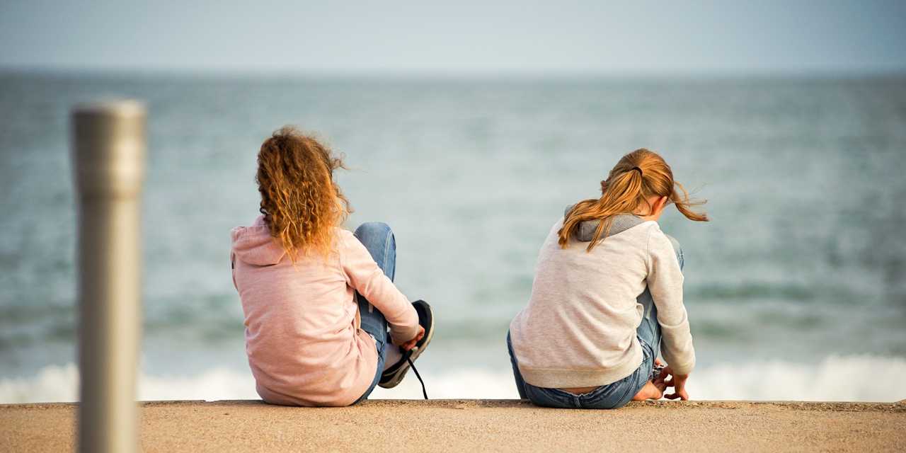 Kaksi henkilöä istuu rannalla