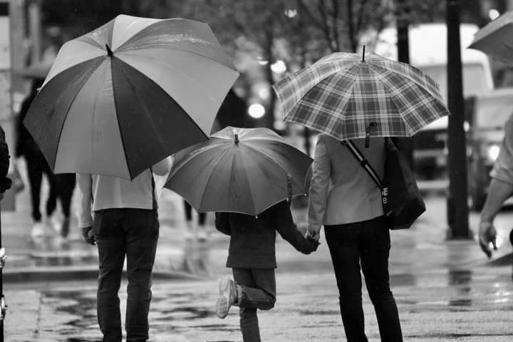 Vanhemmat ja lapsi sateenvarjojen alla