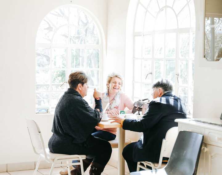 Kolme aikuista istuu ruokapöydän ääressä