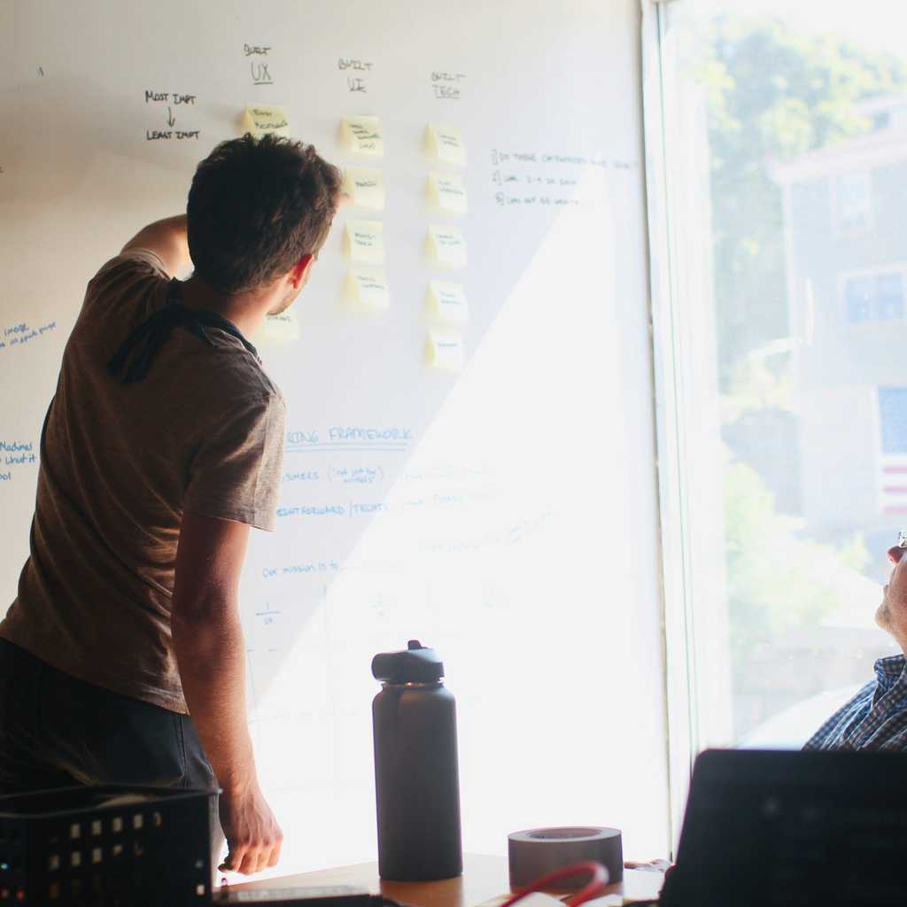 Two people looking at a white board.