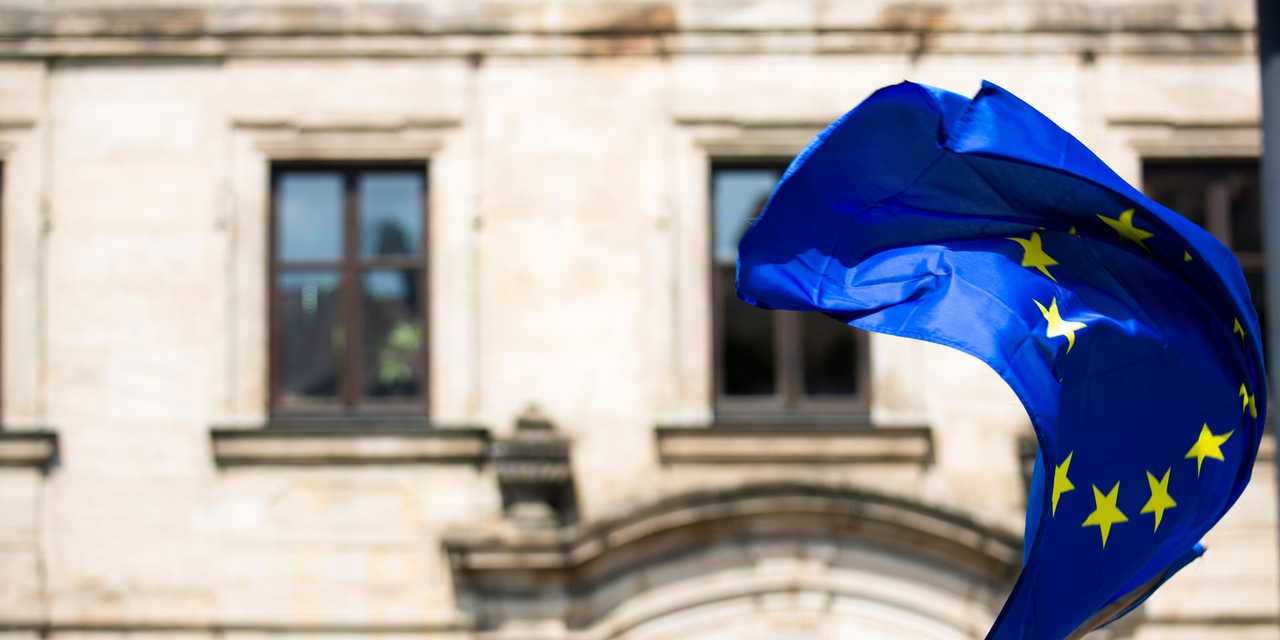 Vind som blåser EU-flagga framför vit byggnad