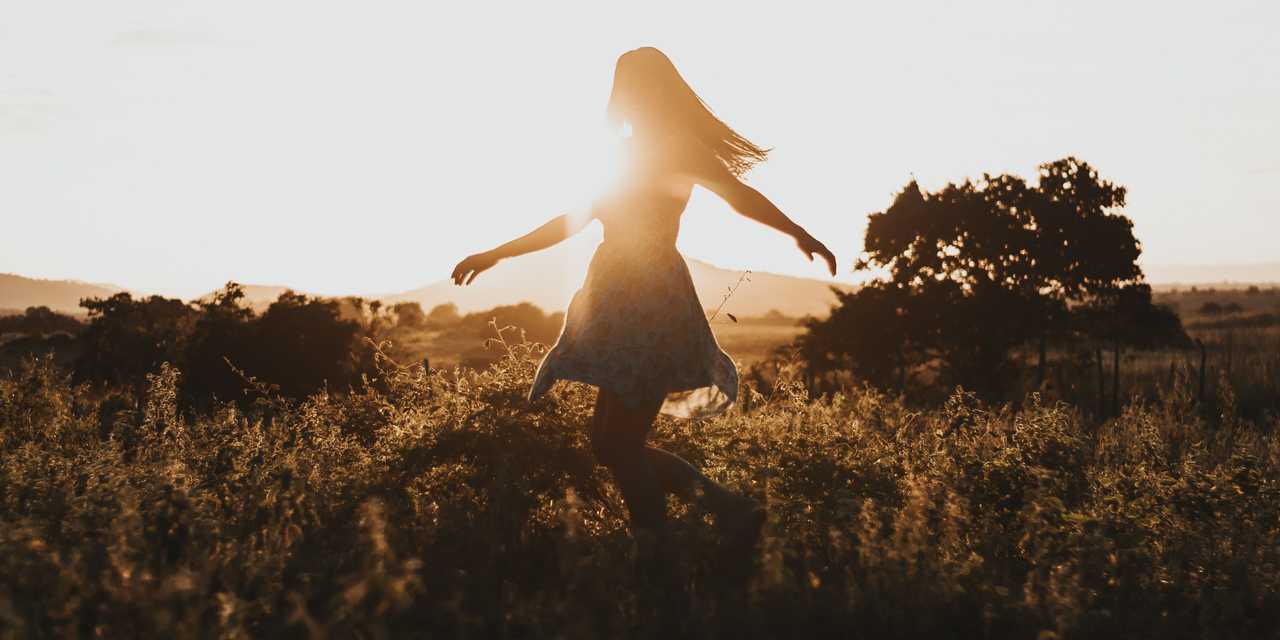Nainen tanssi niityllä auringonlaskussa