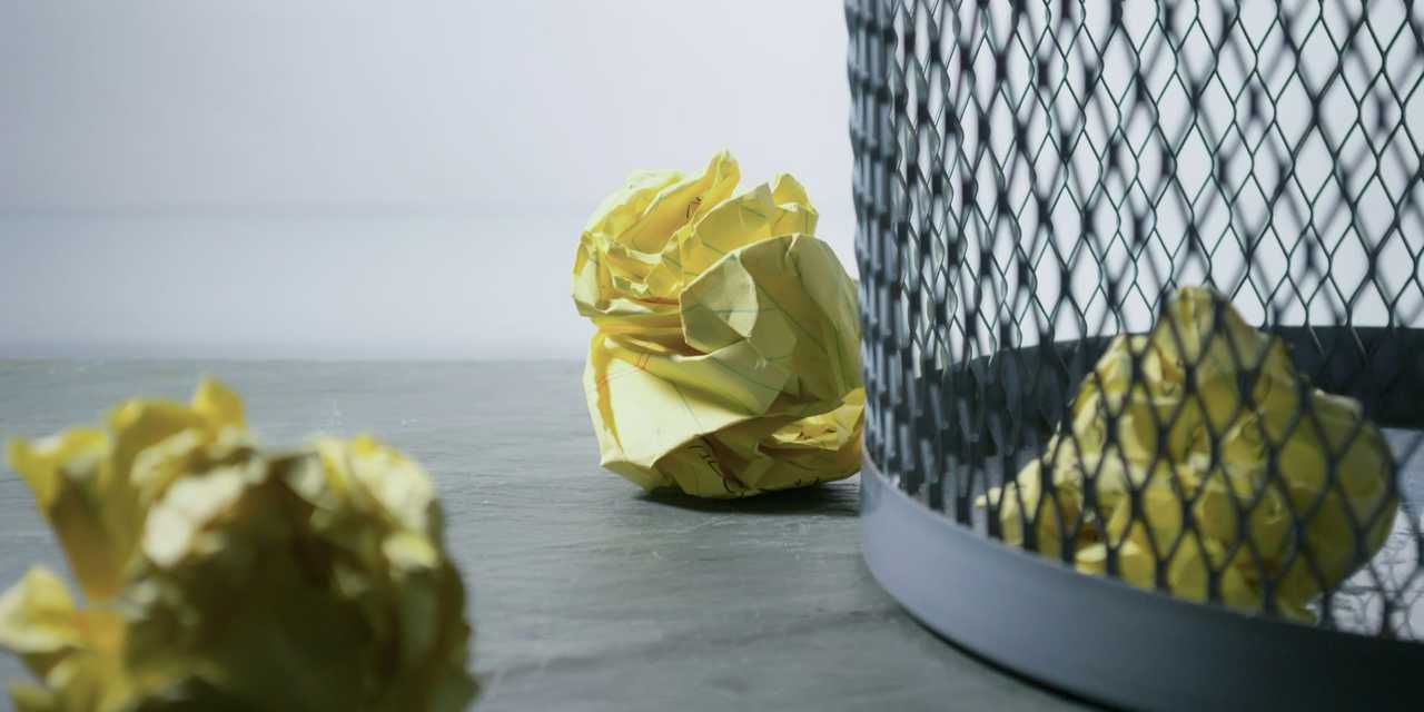 Paper waste in a basket and around on the floor