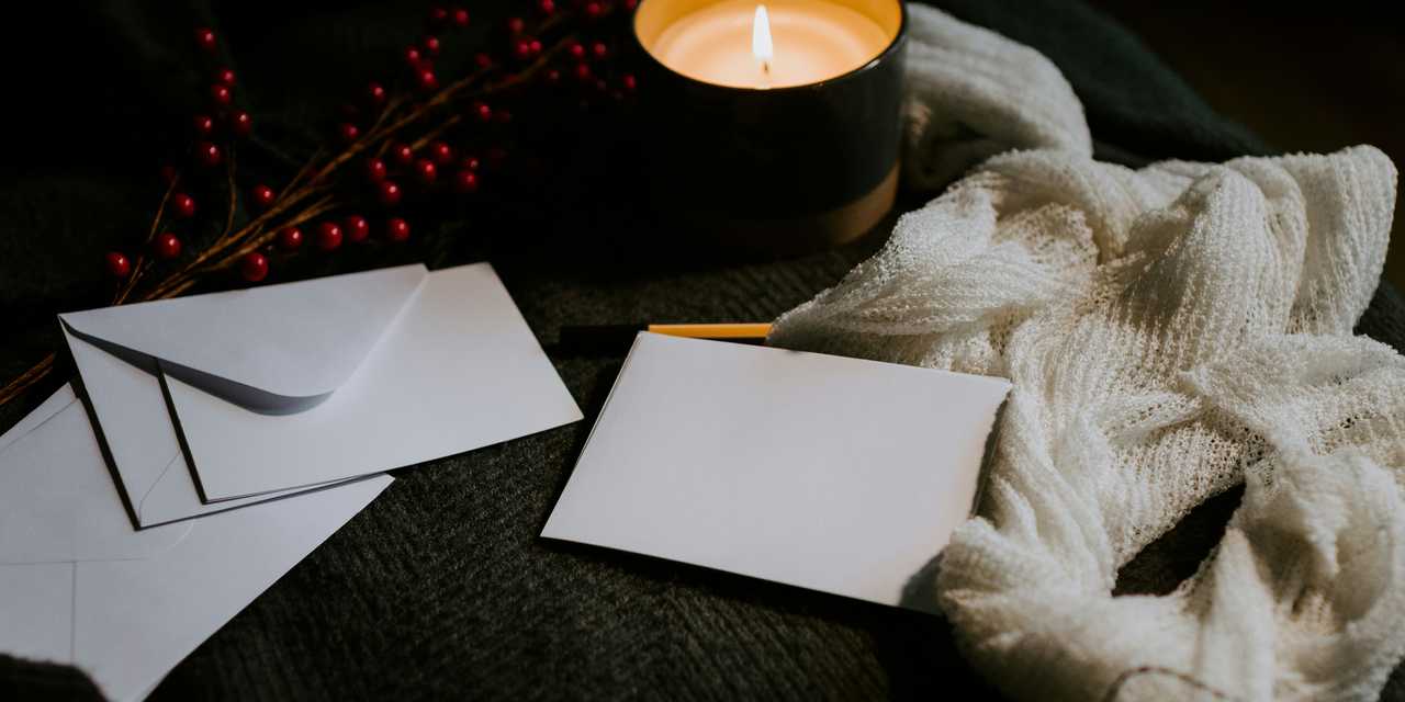 Kirjekuoria, kynttilä ja huovi pöydällä