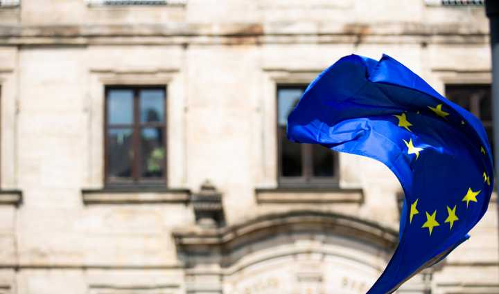 Vind som blåser EU-flagga framför vit byggnad