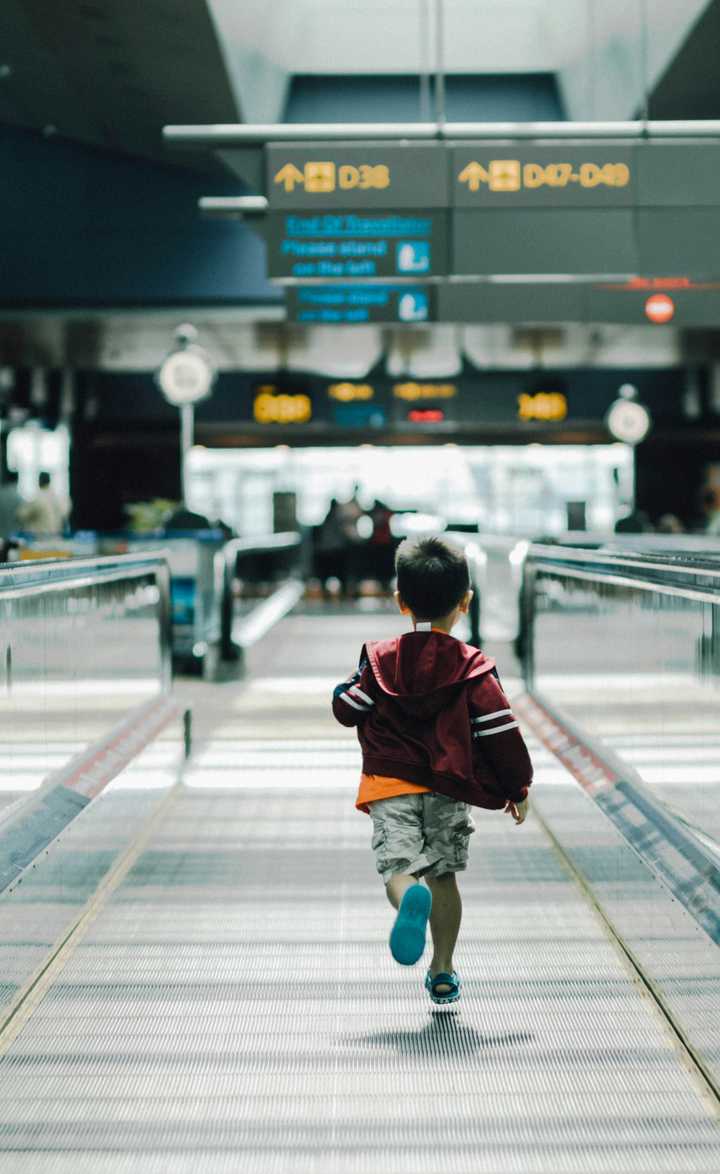 boy running at escalator belt at airport 