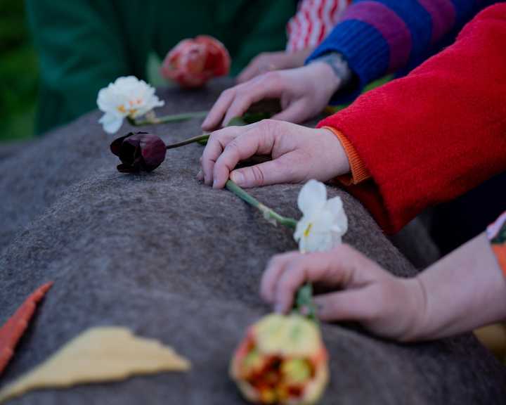 Händer som lägger blommor på filt