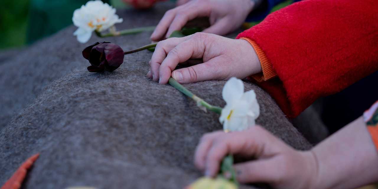 Händer som lägger blommor på filt