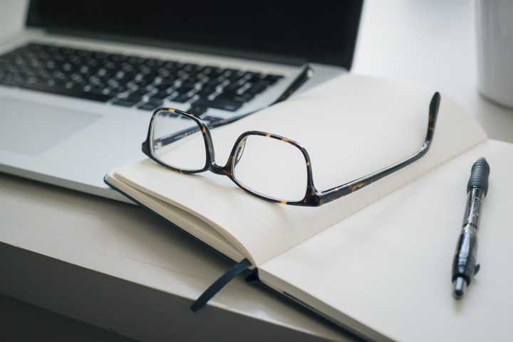 Tietokone, silmälasit ja kirjoitusvälineet