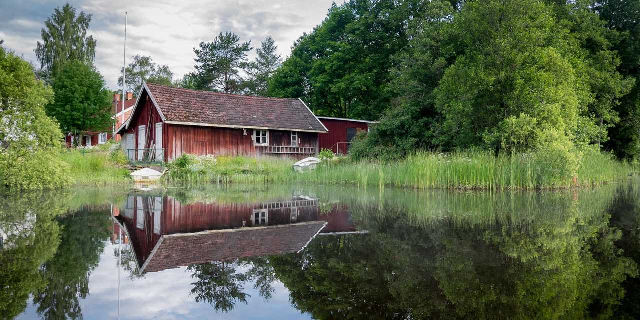 Gammalt rött hus vid en liten sjö