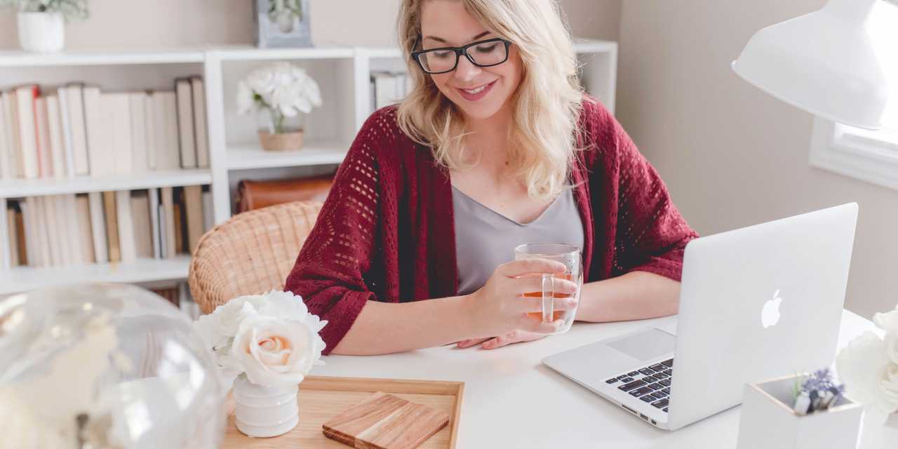 A Woman drinking tea and sitting in front of a laptop