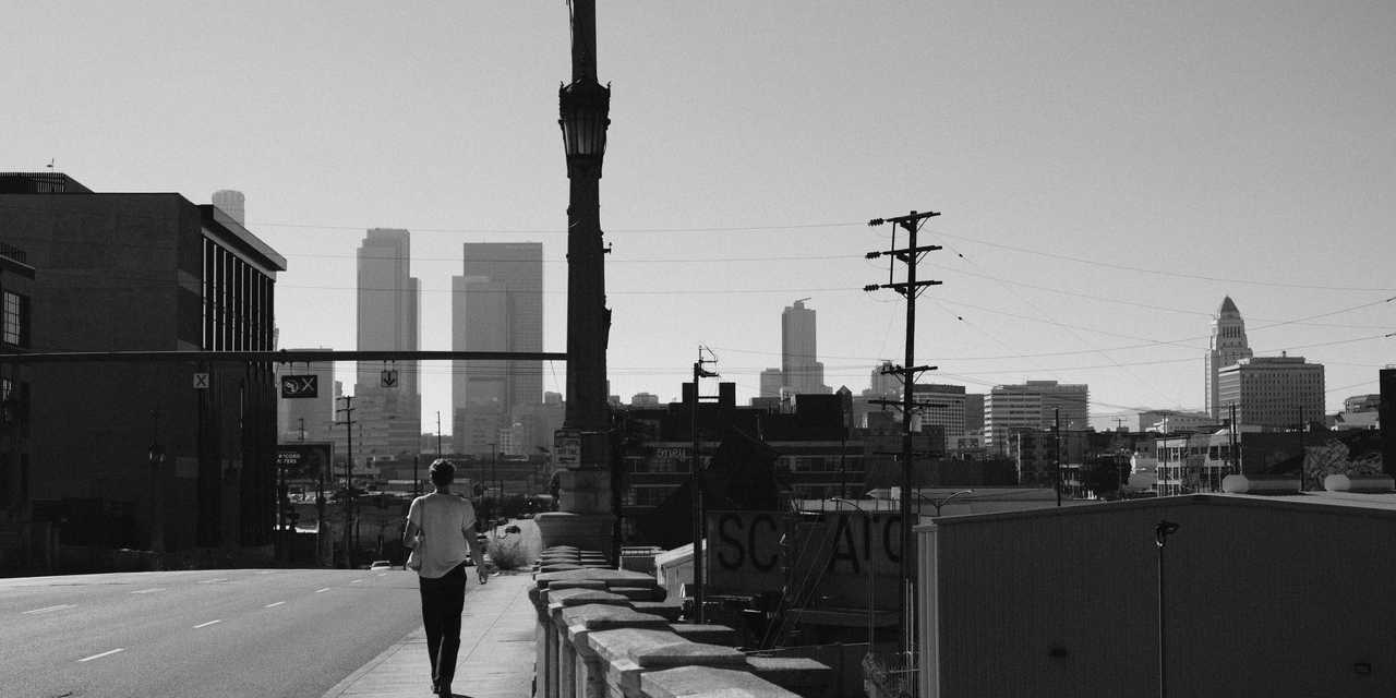 Black and white photo of person walking on a street in a big city