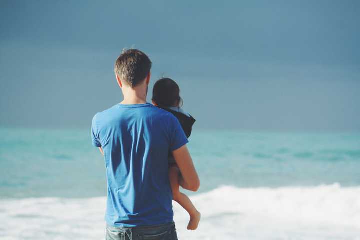 Isä ja lapsi katsovat merelle