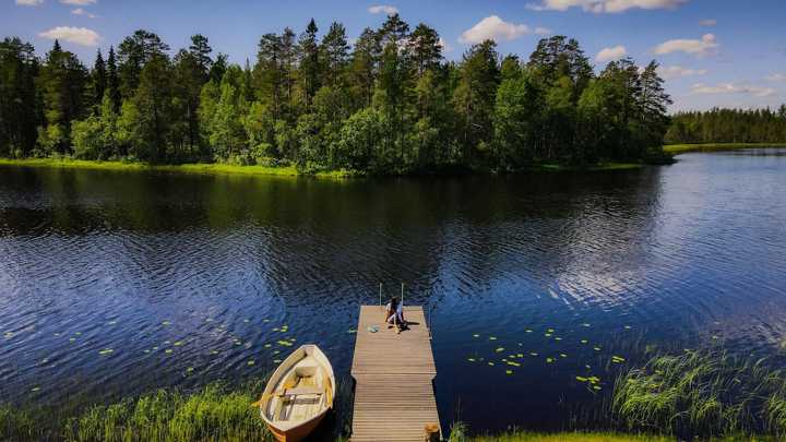 Laituri ja soutuvene vehreän järven rannassa