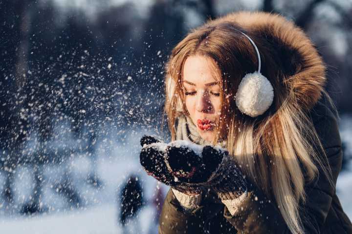 Nainen puhaltaa lunta kämmeneltä