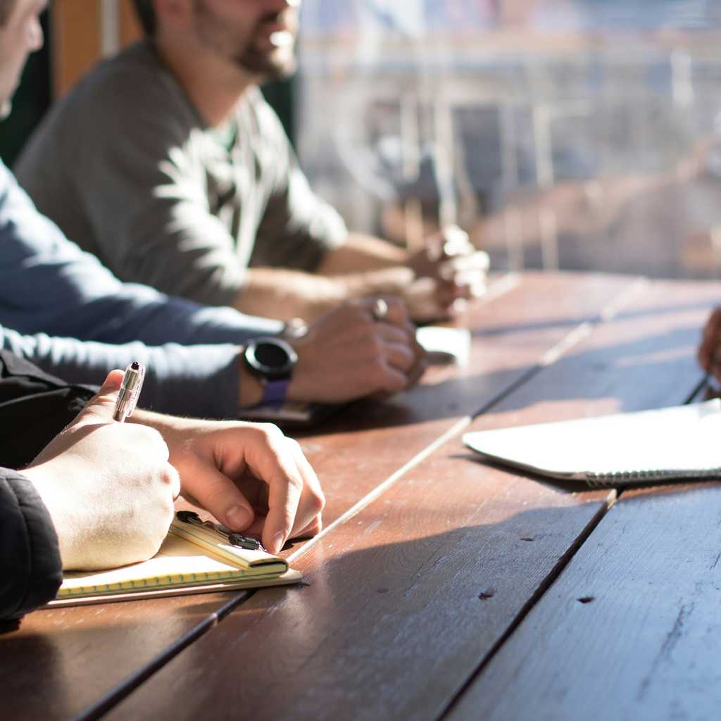 People are gathered around a table with notebooks.