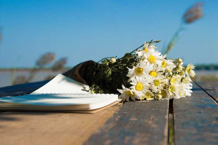 Block med papper och en bukett med vita blommor