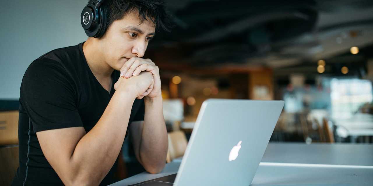 En besvärad man tittar på laptop-skärm 