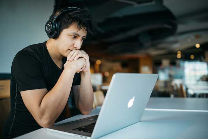 En besvärad man tittar på laptop-skärm 