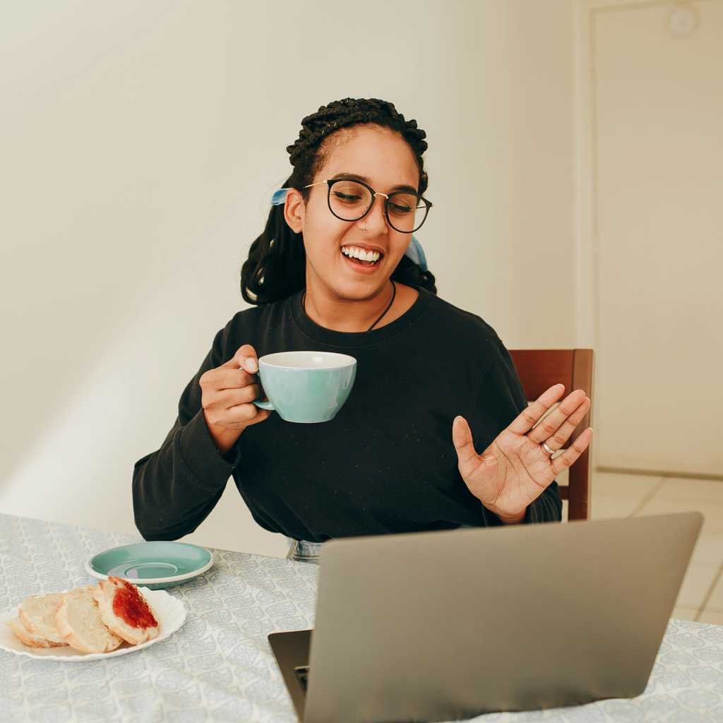 A Woman drinking coffee in a virtual meeting.